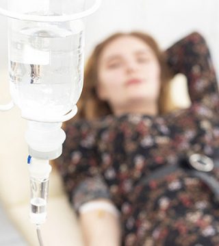 Closeup of saline drip with background Woman patient on the bed get better, when they come for treatment in room hospital. concept healthcare and medicine